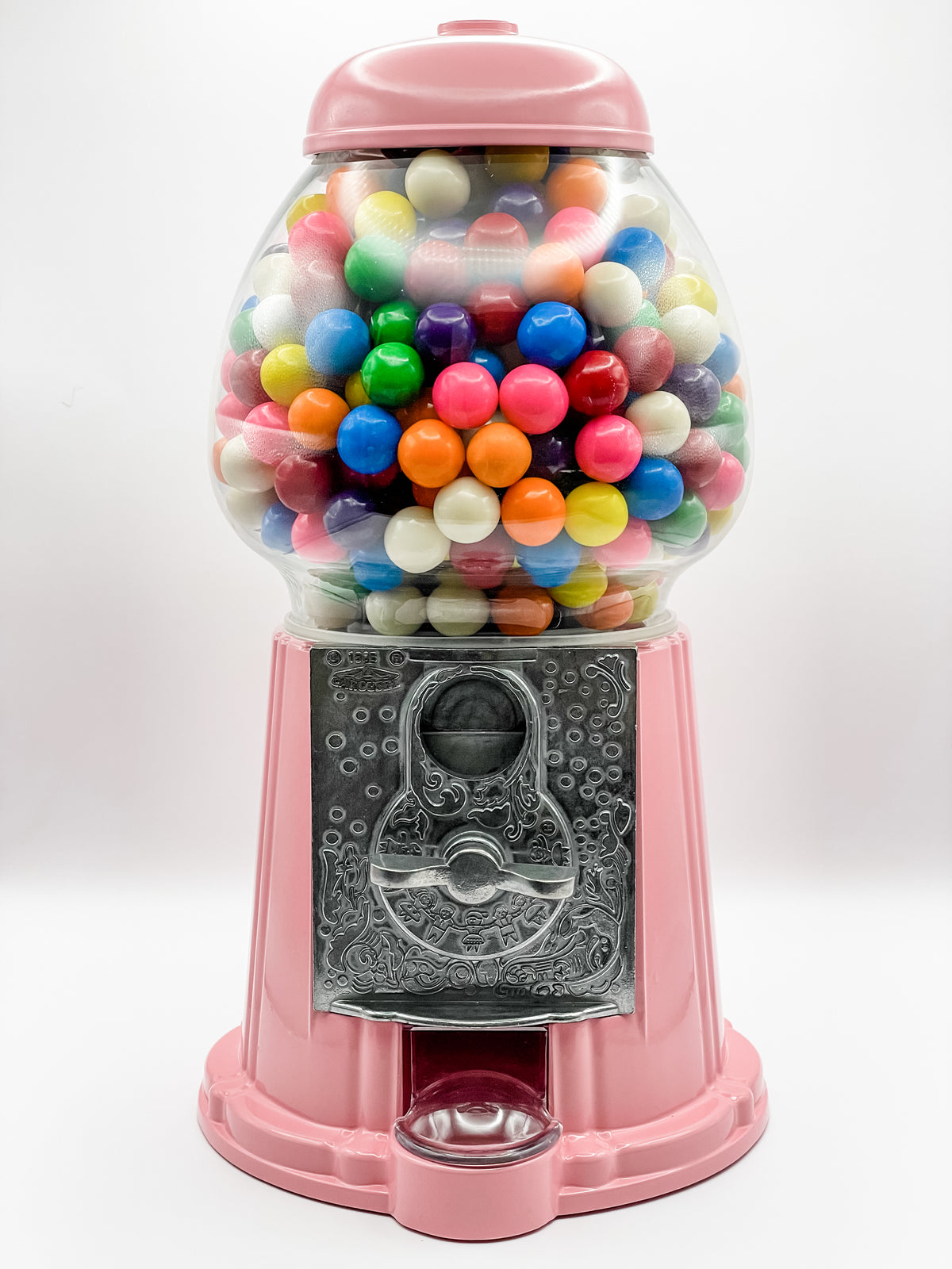 A pink gumball machine filled with multicolored gumballs, featuring a real glass globe and a metal base.
