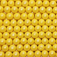 A close-up, top-down view of a dense arrangement of bright yellow metallic gumballs filling the entire frame.